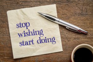 stop wishing, start doing - motivational text on a napkin against grunge wood  grunge wood table, top view with coffee